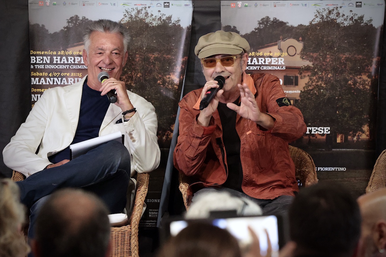 Luca Carboni e il presentatore seduti con microfono in mano, alle loro spalle locandine della rassegna Musart