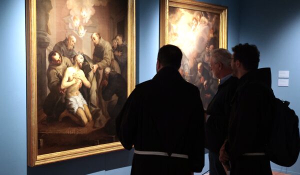 due frati visti di spalle osservano le tele del Nasini raffiguranti San Francesco