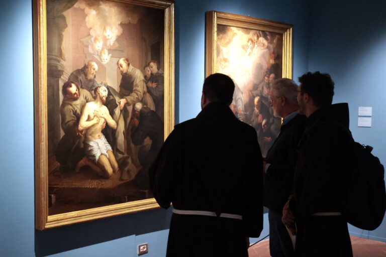 due frati visti di spalle osservano le tele del Nasini raffiguranti San Francesco