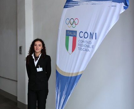 hostess accanto a bandiera Coni con scudetto Italia