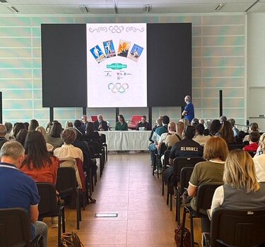 auditorio centro rogerso, pubblico seduto visto di schiena, sullo sfondo il tavolo dei relatori e alle loro spalle locandina dell'evento