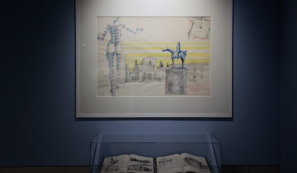 opera dell'artista con cornice bianca, appesa su parete, in basso teca che contiene due libri aperti con disegni dell'artista