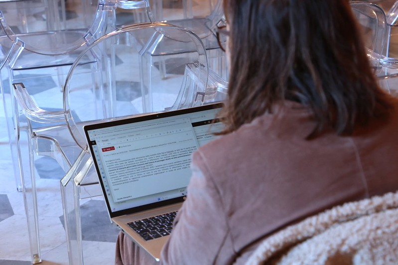 visione di spalle di donna seduta con pc sulle ginocchia in sala pistelli