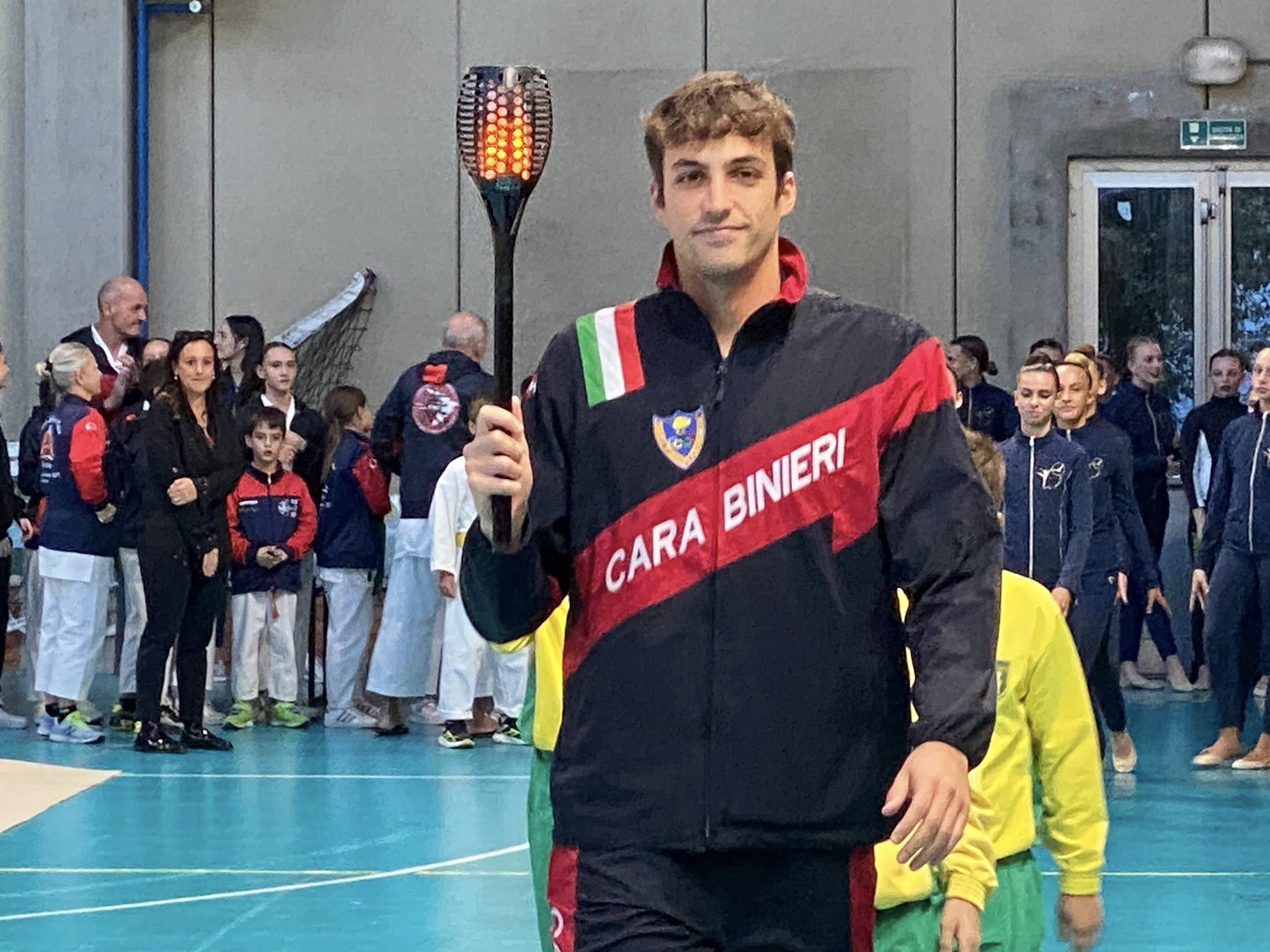 in palestra, primo piano del nuotatore Filippo Megli che porta la fiaccola