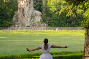 ballerina di spalle in tutu bianco, sullo sfondo la statua del Gigante dell'appennino, parco mediceo di Pratolino