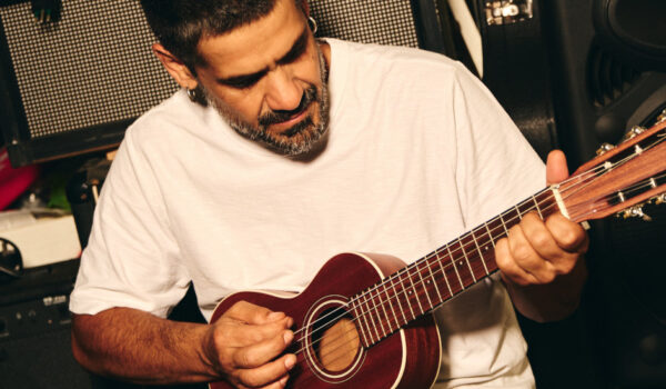 il cantante Mannarino mentre suona una piccola chitarra