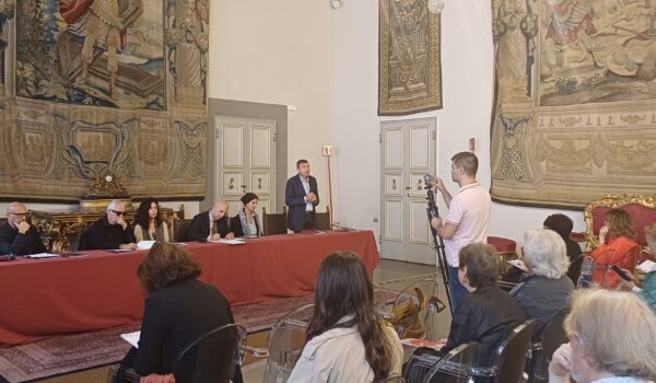 tavolo dei relatori, alle loro spalle arazzo