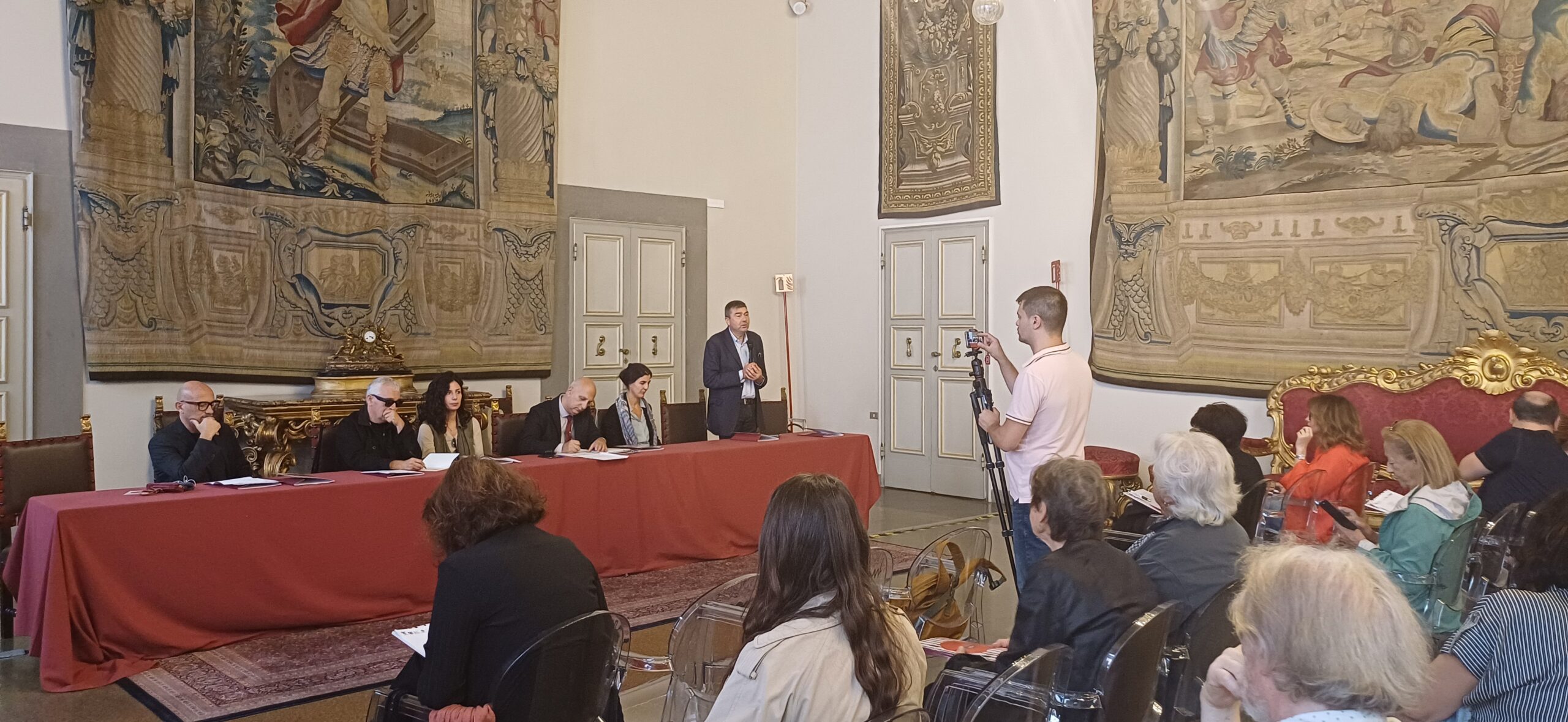 tavolo dei relatori, alle loro spalle arazzo
