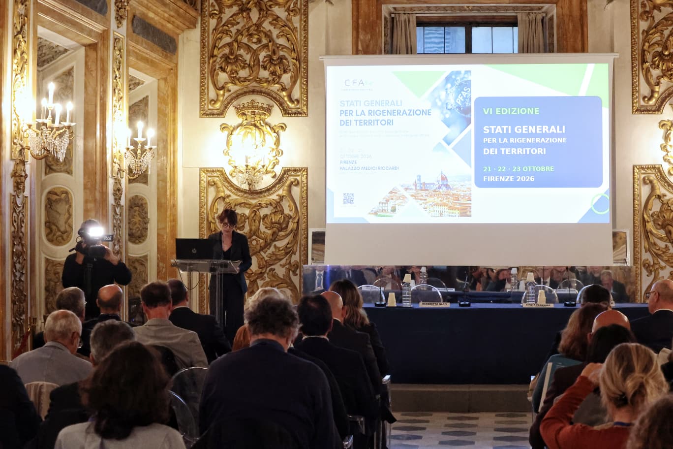 la consigliera sara di maio nel salone degli specchi in piedi al leggio, tavolo dei relatori sullo sfondo, alle loro spalle grande monitor su cui è proiettata slide
