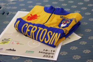 maglia blu e gialla de la Certosina ripiegata sopra opuscolo del percorso della ciclostorica