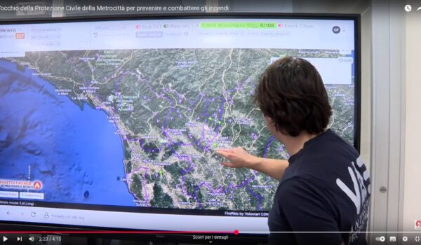 lo sfondo è occupato da un monitor ceh mostra una porzione della Toscana, in primo piano di spalle un operatore indica un punto sulla cartina