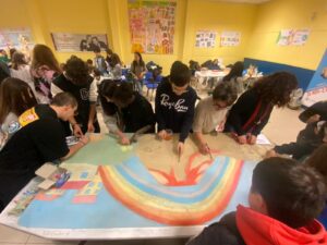 studenti intorno a un tavolo disegnano un arcobaleno