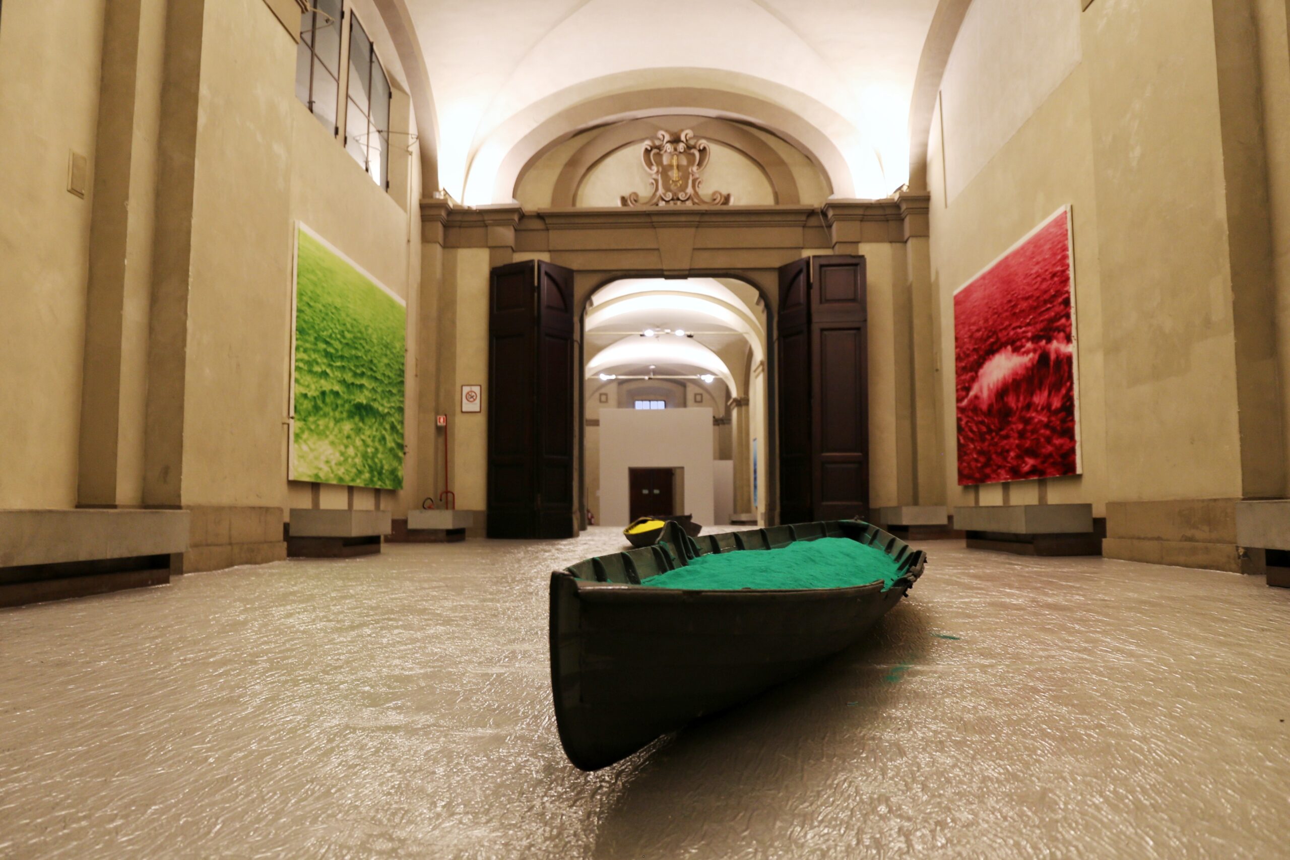 inquadratura dal basso che mostra galleria delle carrozze con barca in primo piano con sabbia verde, alla parete sinistra grande quadro verde, alla parete destra grande quadro rosso