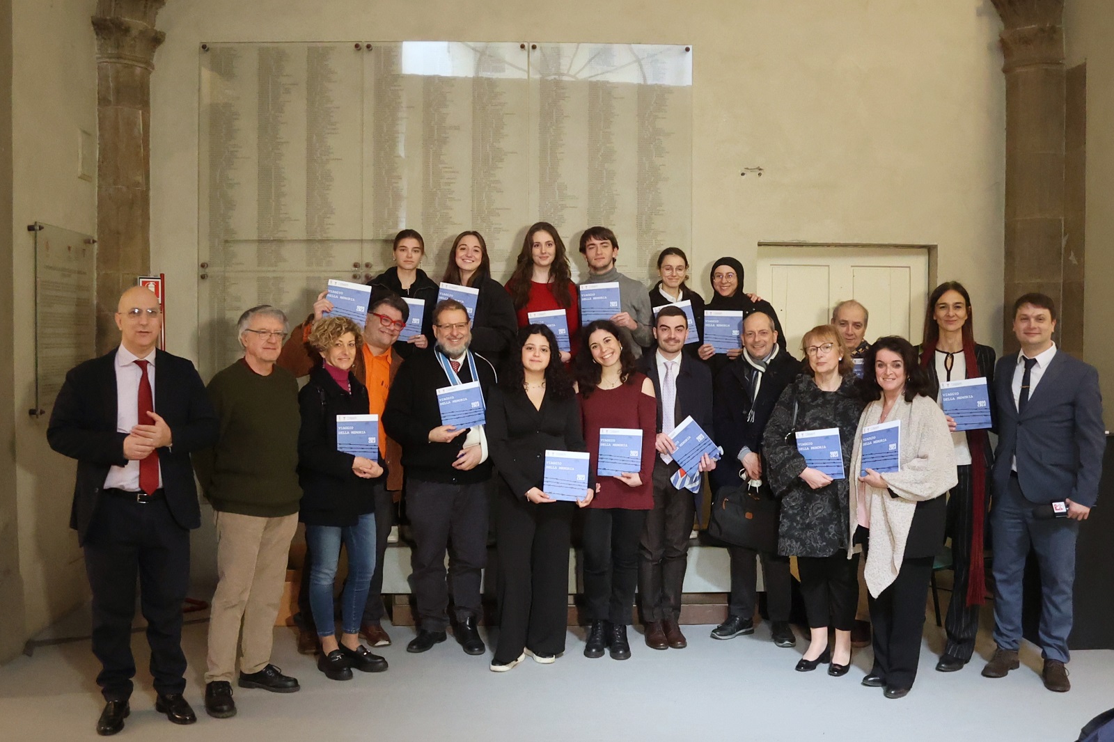 foto di gruppo davanti alla lapide di deportati, nella galleria delle carrozze