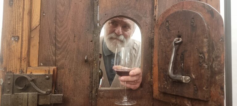 mano con calice spunta da sportellino in portone antico