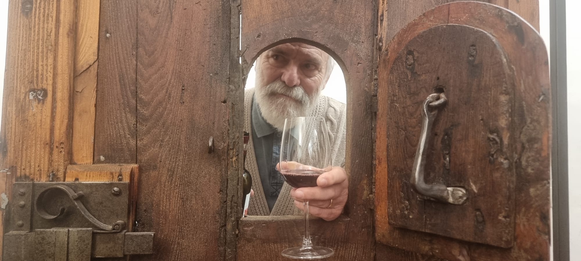 mano con calice spunta da sportellino in portone antico